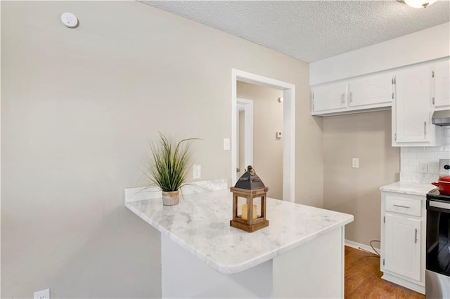 kitchen featuring white cabinetry, tasteful backsplash, stainless steel electric range oven, light hardwood / wood-style flooring, and kitchen peninsula