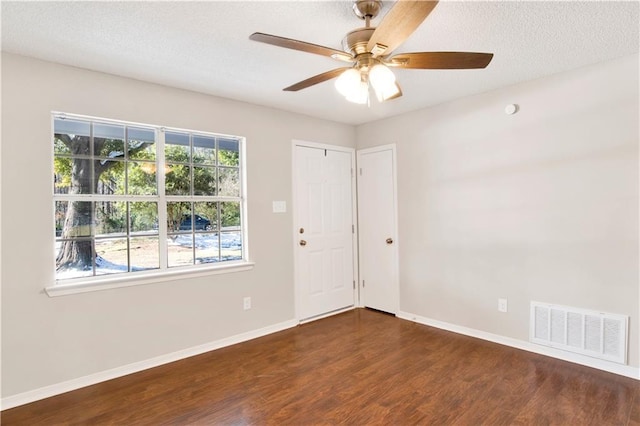 spare room featuring dark wood-type flooring, a textured ceiling, and ceiling fan