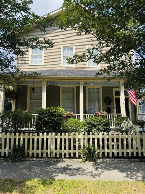 farmhouse-style home with covered porch and a fenced front yard