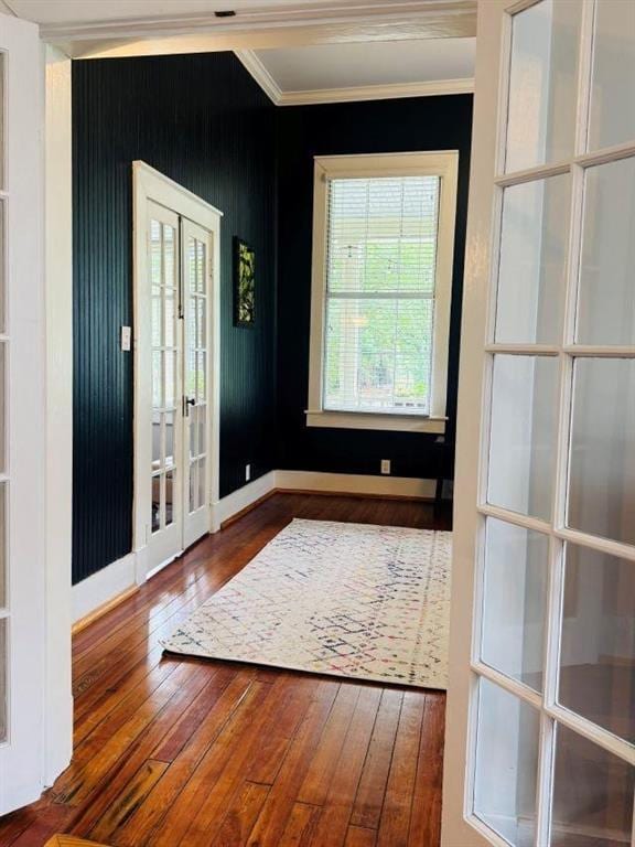 doorway with crown molding, french doors, baseboards, and wood-type flooring