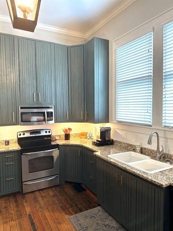 kitchen with a sink, stainless steel appliances, crown molding, light stone counters, and dark wood-style floors