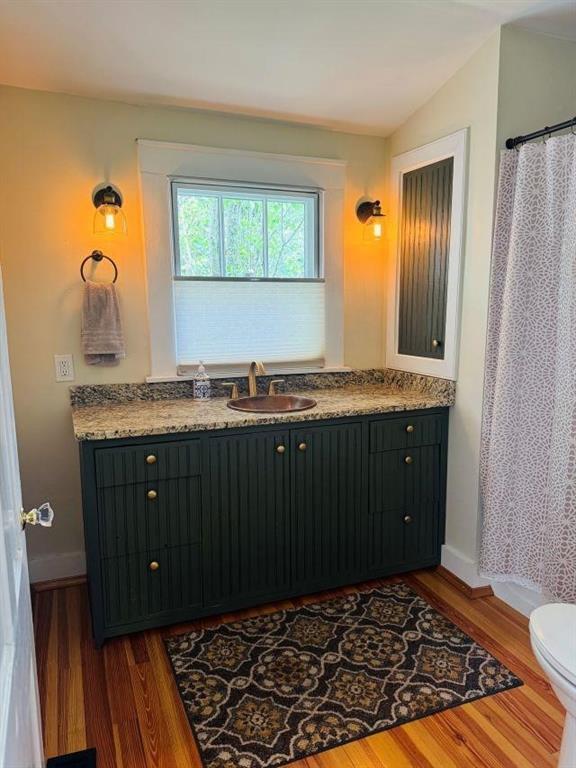 bathroom featuring toilet, baseboards, vanity, and wood finished floors