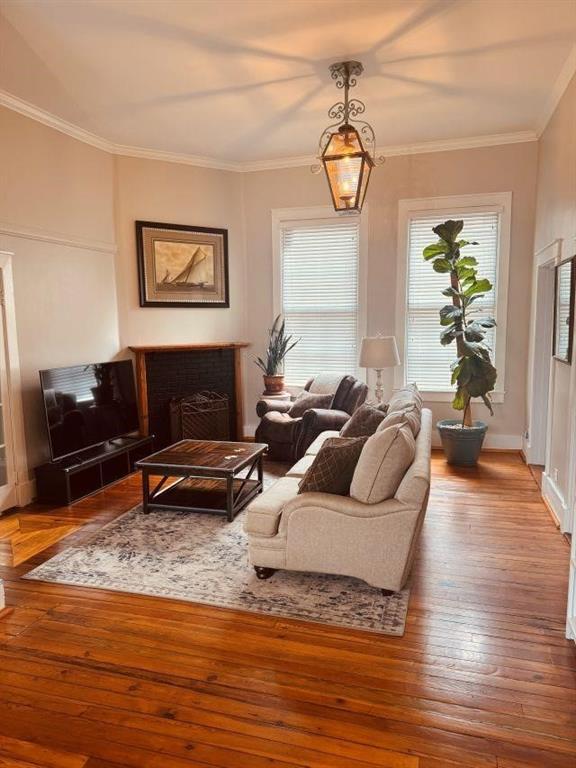 living area with a fireplace, crown molding, and hardwood / wood-style floors