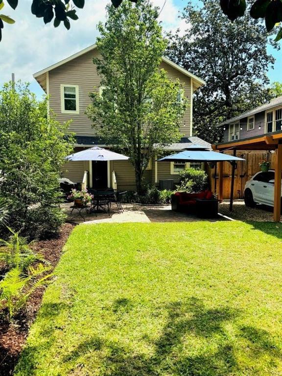 back of property with a yard, a patio area, a carport, and fence