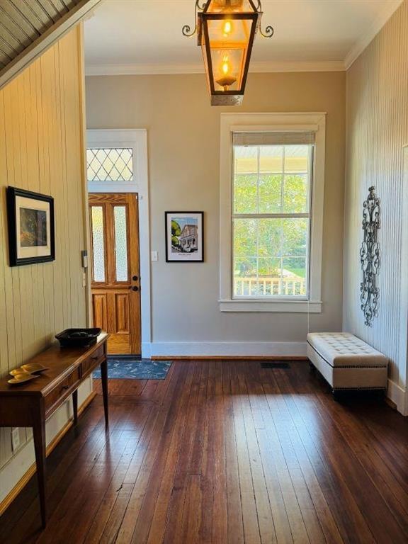foyer featuring baseboards, visible vents, crown molding, and dark wood-style floors