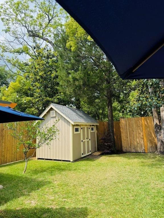 view of yard with a fenced backyard, a shed, and an outbuilding