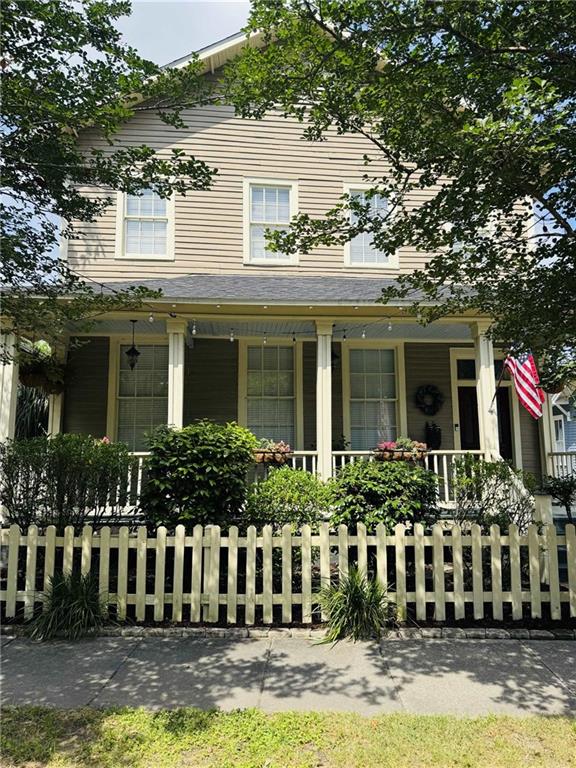 farmhouse inspired home with a porch and a fenced front yard