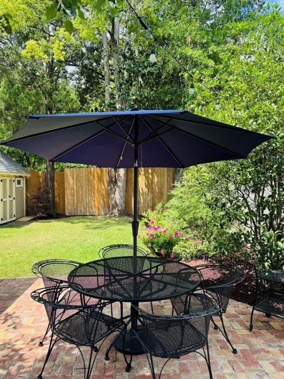 view of patio with fence, a storage shed, outdoor dining space, and an outdoor structure