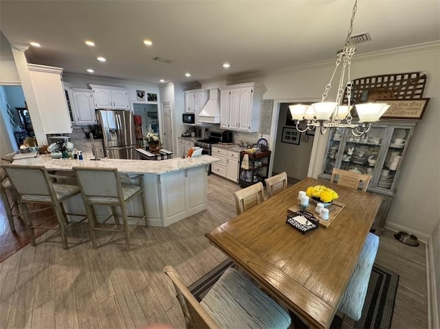 5541 Riverwood Lndg, Theodore, AL 36582 - dining room with light wood-style flooring, a chandelier, ornamental molding, and recessed lighting