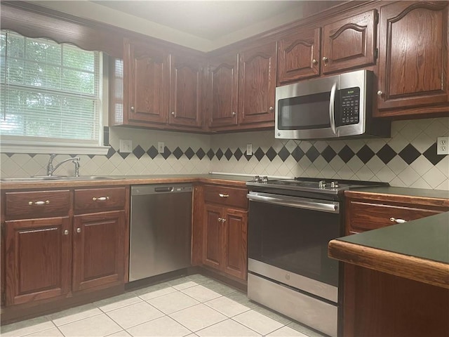 kitchen with tasteful backsplash, sink, light tile patterned floors, and appliances with stainless steel finishes