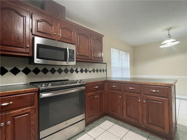 kitchen with light tile patterned flooring, kitchen peninsula, backsplash, and appliances with stainless steel finishes