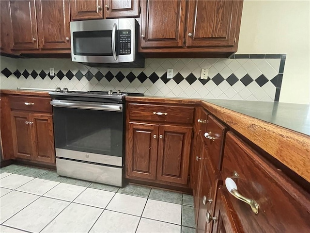 kitchen with tasteful backsplash, dark brown cabinets, light tile patterned floors, and stainless steel appliances