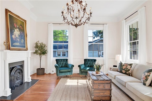living area featuring wood-type flooring, a chandelier, crown molding, a fireplace, and baseboards