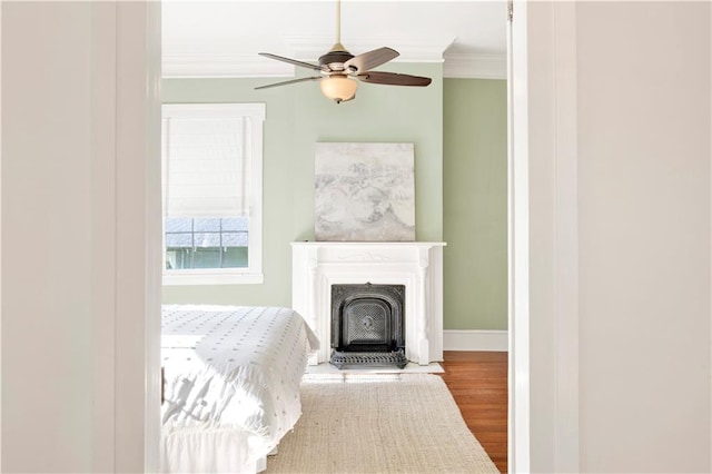 unfurnished bedroom featuring crown molding, wood finished floors, baseboards, and ceiling fan
