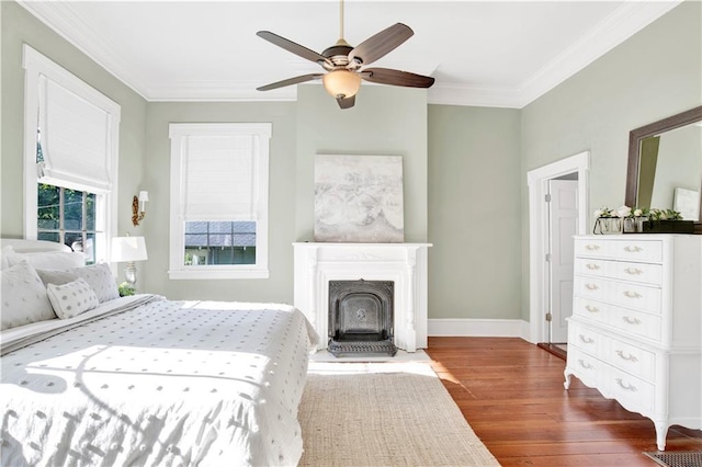 bedroom with wood finished floors, crown molding, baseboards, and ceiling fan