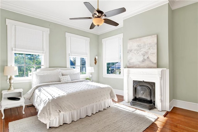 bedroom featuring multiple windows, crown molding, hardwood / wood-style flooring, baseboards, and ceiling fan