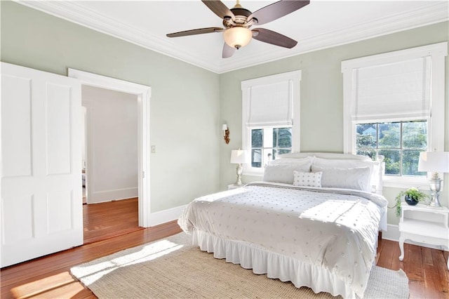 bedroom with ornamental molding, wood finished floors, baseboards, and ceiling fan