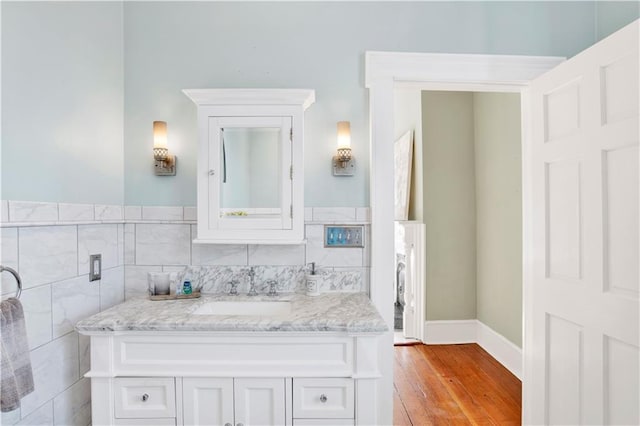 bathroom featuring wood finished floors, vanity, and tile walls