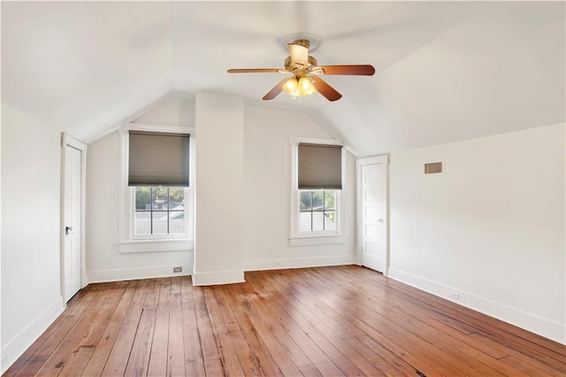 additional living space featuring light wood-style floors, lofted ceiling, a ceiling fan, baseboards, and healthy amount of natural light