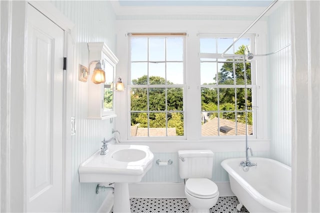 full bath featuring a freestanding tub, tile patterned floors, and toilet