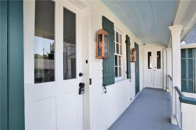 view of exterior entry with covered porch and french doors