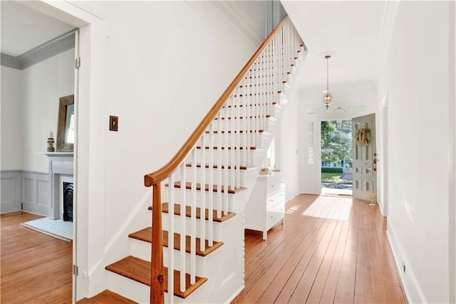 stairs featuring hardwood / wood-style floors, ornamental molding, and a fireplace