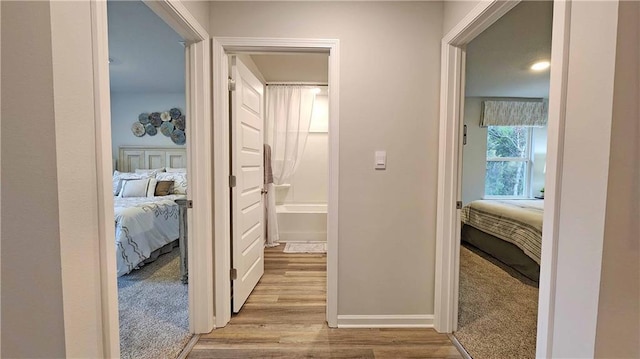 corridor with light wood-style flooring and baseboards