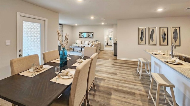 dining room with recessed lighting, visible vents, baseboards, light wood-type flooring, and wet bar