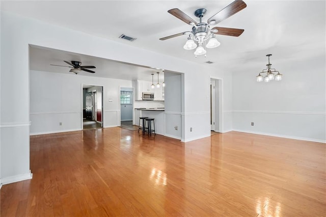 5175 Somerset Dr W, Mobile, AL 36619 - unfurnished living room with a ceiling fan, wood finished floors, baseboards, and a chandelier