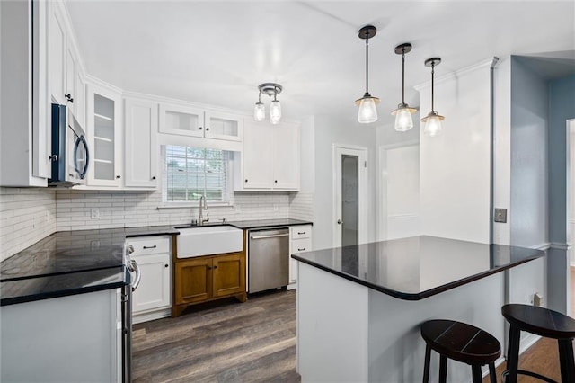 5175 Somerset Dr W, Mobile, AL 36619 - kitchen featuring appliances with stainless steel finishes, a sink, dark countertops, dark wood-type flooring, and tasteful backsplash