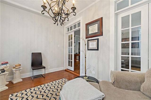 sitting room with a notable chandelier, wood finished floors, baseboards, ornamental molding, and french doors