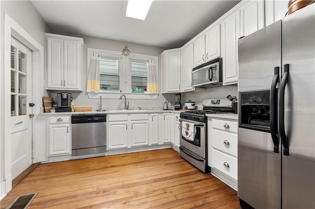 kitchen featuring stainless steel appliances, white cabinets, and a sink