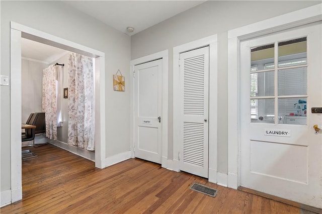 foyer with wood finished floors, visible vents, and baseboards