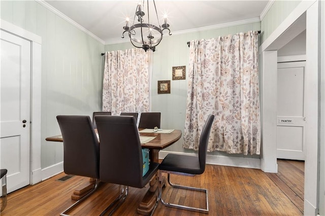 dining space with a chandelier, wood finished floors, visible vents, and crown molding