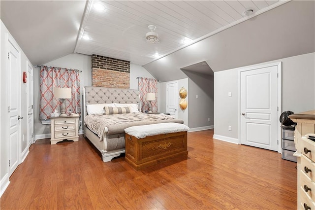 bedroom featuring lofted ceiling, baseboards, and wood finished floors