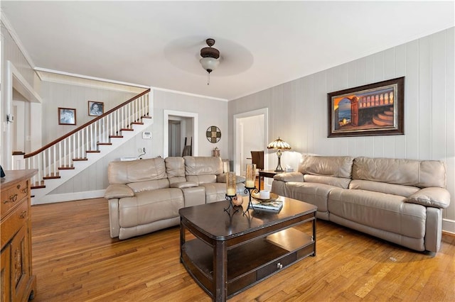 living room featuring ceiling fan, stairway, light wood-type flooring, and crown molding