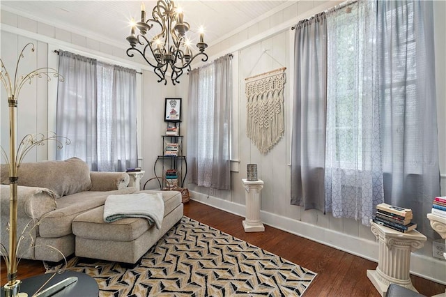 living area featuring baseboards, a chandelier, dark wood finished floors, and crown molding