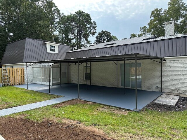 back of property with a lawn and a carport