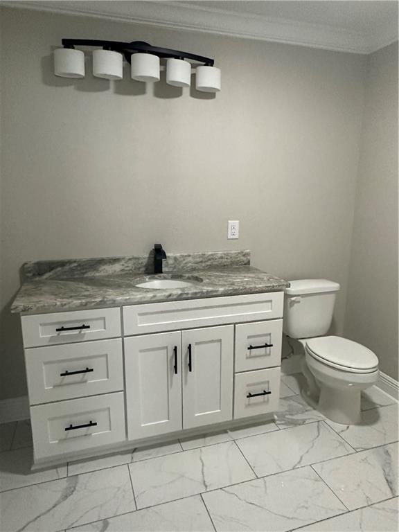 bathroom with toilet, ornamental molding, vanity, and tile flooring