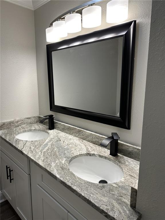 bathroom with crown molding and dual bowl vanity