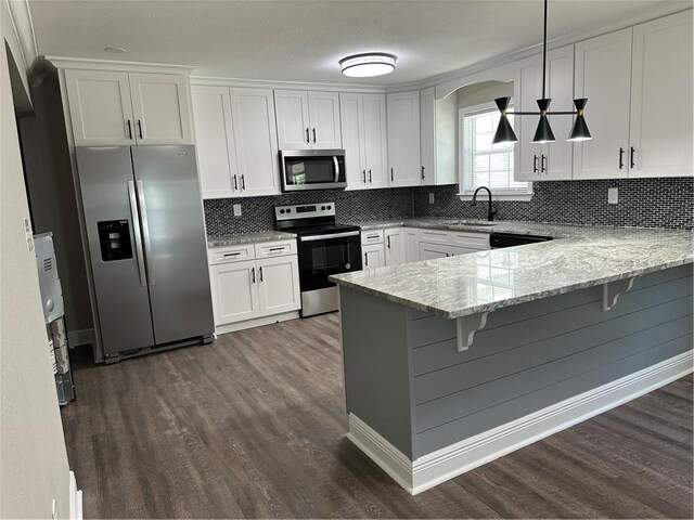 kitchen featuring dark hardwood / wood-style floors, white cabinets, a breakfast bar, stainless steel appliances, and tasteful backsplash