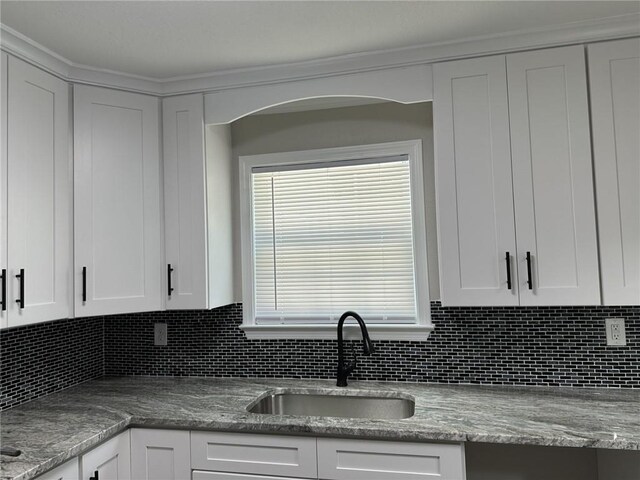 kitchen featuring white cabinets, backsplash, sink, and light stone counters