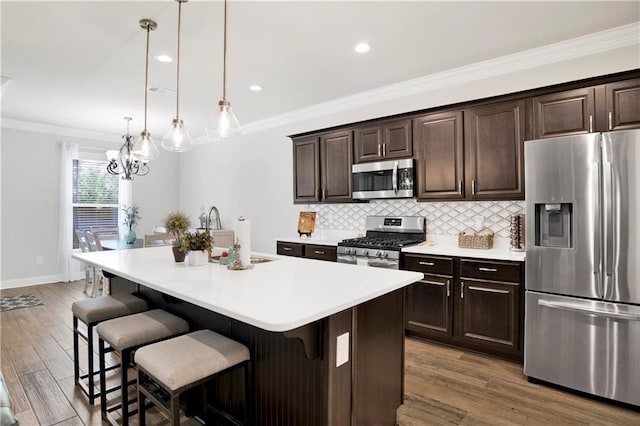 1484 Fenton Cir, Foley, AL 36535 - kitchen featuring appliances with stainless steel finishes, a kitchen breakfast bar, tasteful backsplash, wood finished floors, and light countertops