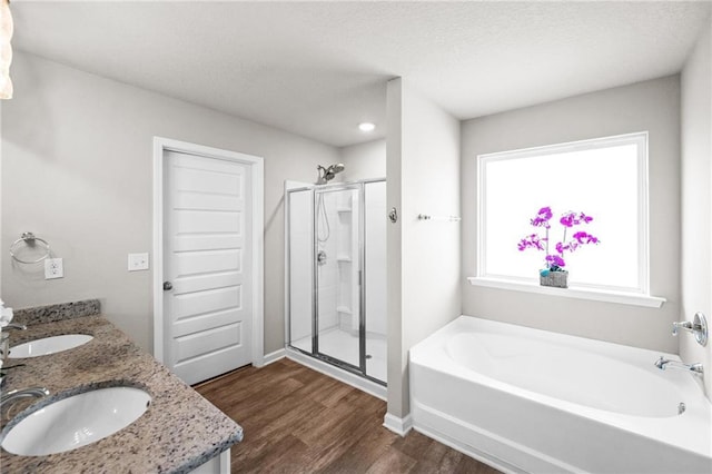 bathroom with wood-type flooring, separate shower and tub, and vanity