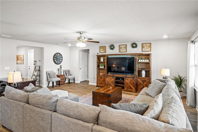 living room featuring ceiling fan, light hardwood / wood-style floors, and a textured ceiling