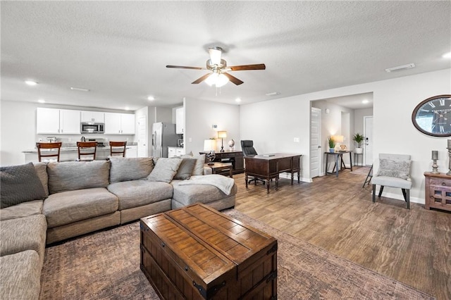 living room with wood-type flooring, ceiling fan, and a textured ceiling