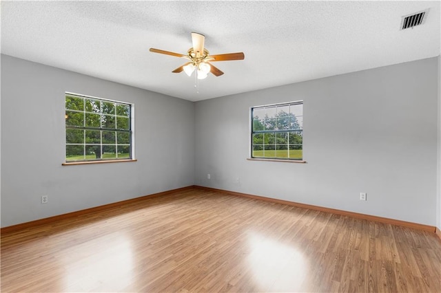 unfurnished room featuring a textured ceiling, ceiling fan, visible vents, baseboards, and light wood-type flooring