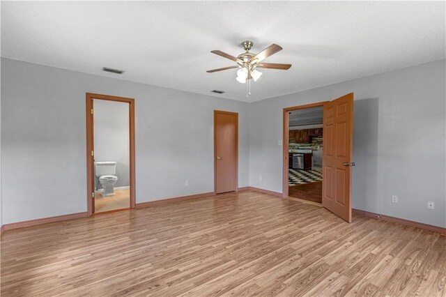 unfurnished bedroom with ceiling fan, light wood-type flooring, and connected bathroom