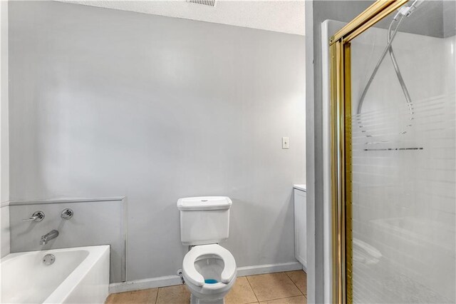 bathroom featuring toilet, a tub to relax in, a textured ceiling, and tile patterned floors