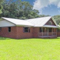 exterior space featuring covered porch, metal roof, and a front lawn